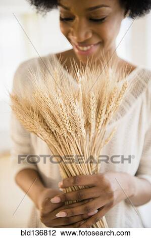 Stock Image - African American woman holding bunch of wheat. Fotosearch