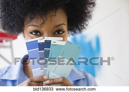 Stock Image - African American woman holding paint swatches. Fotosearch