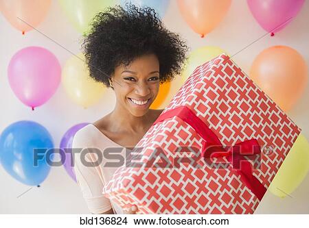 African American woman holding wrapped gift at birthday party View Large Photo Image Picture - African American woman holding wrapped gift at birthday party. Fotosearch