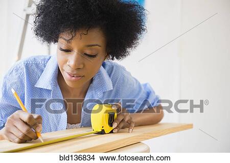 Picture - African American woman measuring wood. Fotosearch