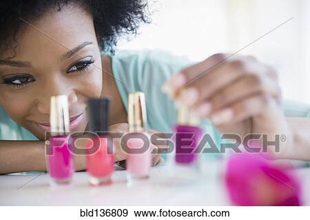Stock Photo - African American woman painting her nails. Fotosearch