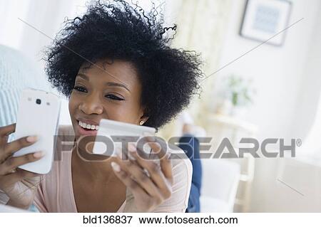 Stock Photo - African American woman shopping on cell phone. Fotosearch