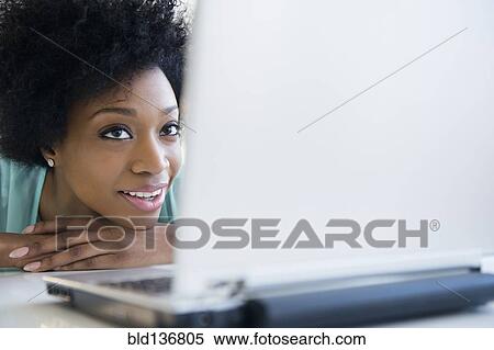 Stock Photography - African American woman using laptop at table. Fotosearch
