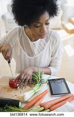 Picture - African American woman using tablet computer to cook. Fotosearch