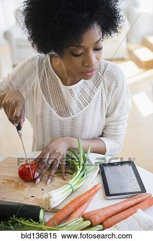 Stock Photography - African American woman using tablet computer to cook. Fotosearch