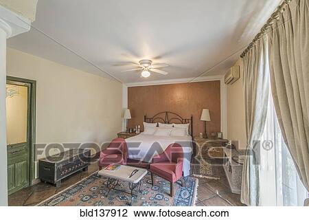 Bed, chairs and trunks in traditional hotel room View Large Photo Image Stock Image - Bed, chairs and trunks in traditional hotel room. Fotosearch