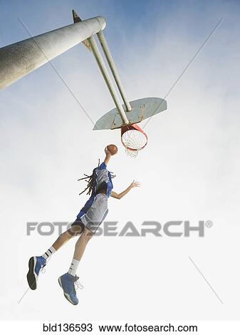 Stock Image - Black basketball player dunking ball in hoop. Fotosearch