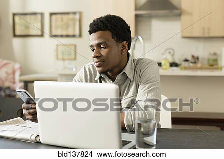 Picture - Black businessman working at breakfast table. Fotosearch