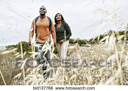 Stock Photo - Black couple hiking on rural hillside. Fotosearch