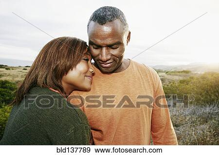 Stock Photo - Black couple hugging on rural hillside. Fotosearch