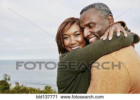Stock Image - Black couple hugging outdoors. Fotosearch