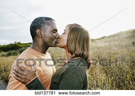 Stock Image - Black couple kissing on rural path. Fotosearch