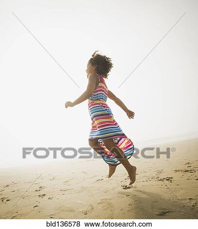 Stock Photo - Black girl playing on beach. Fotosearch