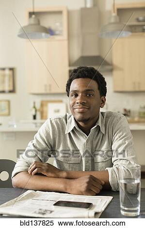 Stock Photography - Black man reading newspaper at breakfast table. Fotosearch