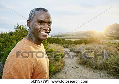 Stock Image - Black man smiling on rural hillside. Fotosearch