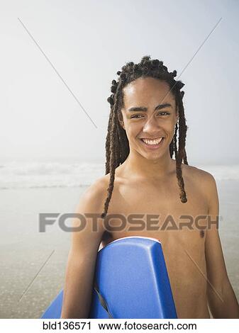 Black Teenage Boy Carrying Boogie Board On Beach Stock Image