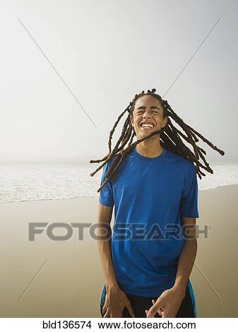 Picture - Black teenage boy laughing on beach. Fotosearch