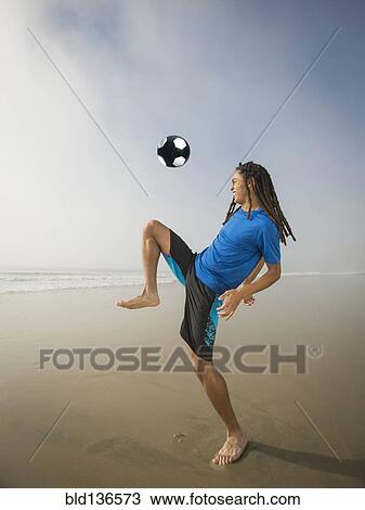 Black teenage boy playing with soccer ball on beach View Large Photo Image Stock Image - Black teenage boy playing with soccer ball on beach. Fotosearch