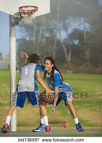 Stock Photo - Black teenage boys playing basketball on court. Fotosearch