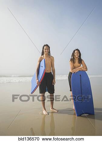 Black teenage boys with boogie boards on beach View Large Photo Image Stock Image - Black teenage boys with boogie boards on beach. Fotosearch