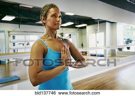 Stock Photograph - Black woman meditating in yoga studio. Fotosearch