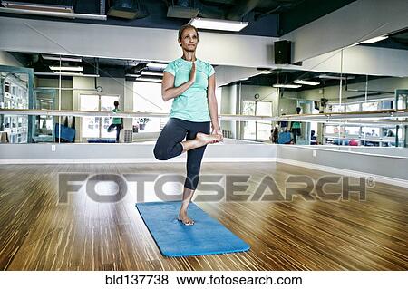Stock Photo - Black woman practicing yoga in studio. Fotosearch