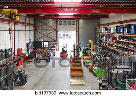 Stock Image - Blurred view of worker using machinery in warehouse. Fotosearch