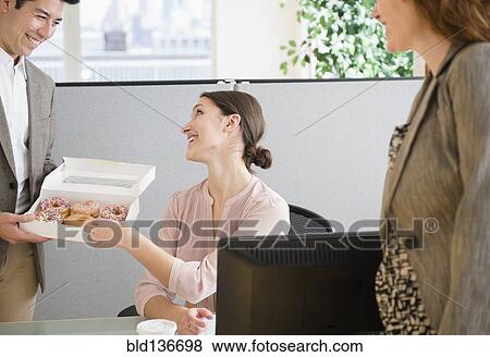 Stock Photo - Business people having donuts in office. Fotosearch