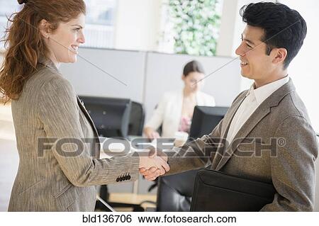 Stock Photograph - Business people shaking hands in office. Fotosearch