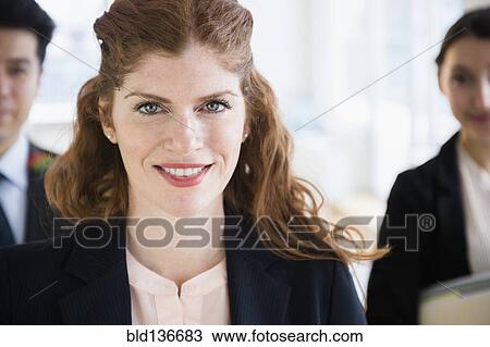 Stock Image - Business people smiling in office. Fotosearch
