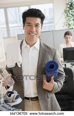 Stock Photography - Businessman carrying workout gear in office. Fotosearch