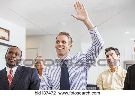 Stock Image - Businessman raising his hand in office. Fotosearch