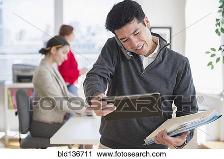 Stock Image - Businessman talking on cell phone in office. Fotosearch