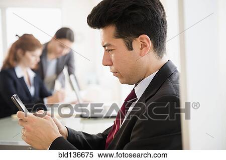 Stock Photography - Businessman using cell phone in office. Fotosearch