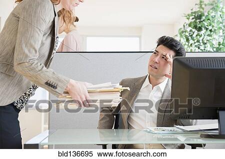 Businesswoman giving colleague stack of papers View Large Photo Image Stock Photography - Businesswoman giving colleague stack of papers. Fotosearch