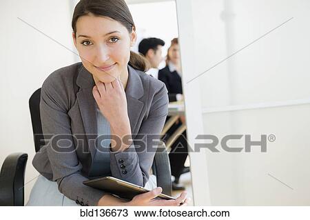 Stock Image - Businesswoman smiling in office. Fotosearch
