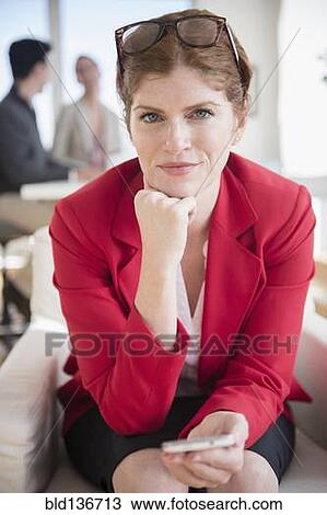 Stock Image - Businesswoman using cell phone in office. Fotosearch