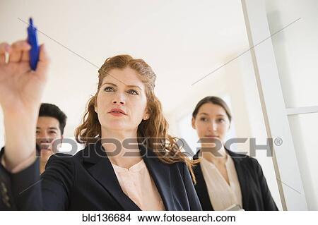Picture - Businesswoman writing on window in office. Fotosearch