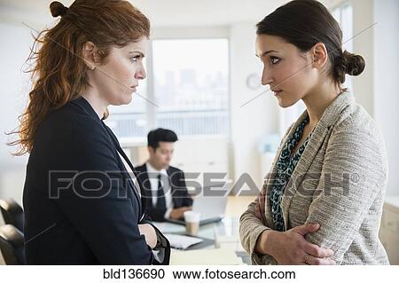 Businesswomen glaring at each other in office View Large Photo Image Stock Image - Businesswomen glaring at each other in office. Fotosearch