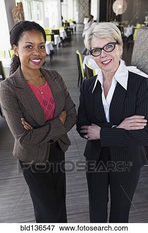 Businesswomen smiling together in restaurant View Large Photo Image Stock Photo - Businesswomen smiling together in restaurant. Fotosearch