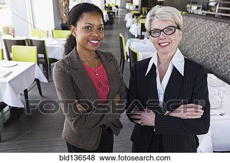 Stock Photo - Businesswomen smiling together in restaurant. Fotosearch