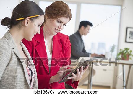 Stock Photo - Businesswomen using digital tablet in office. Fotosearch