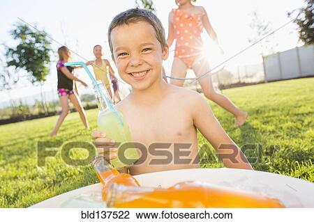Stock Image - Caucasian boy drinking soda in backyard. Fotosearch