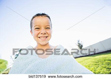Stock Photo - Caucasian boy playing with towel in backyard. Fotosearch