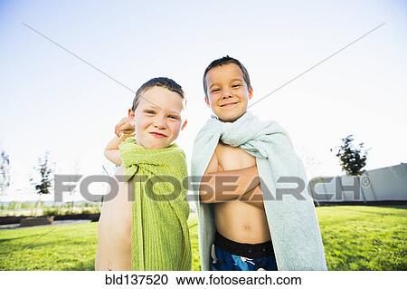 Stock Image - Caucasian boys wearing towel capes in backyard. Fotosearch
