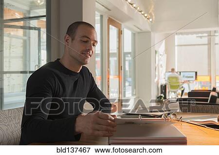 Stock Photo - Caucasian businessman reading at desk. Fotosearch