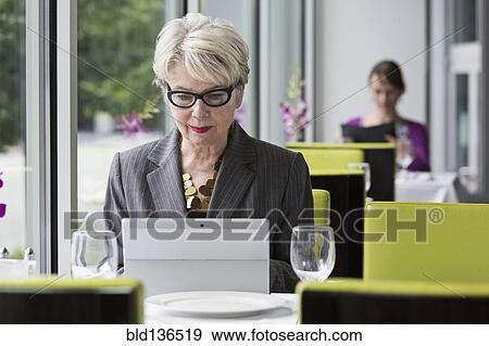Stock Photo - Caucasian businesswoman using tablet computer in restaurant. Fotosearch