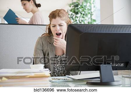 Stock Photograph - Caucasian businesswoman yawning at desk. Fotosearch