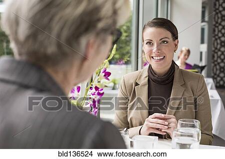 Picture - Caucasian businesswomen talking in restaurant. Fotosearch