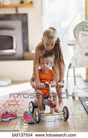 Picture - Caucasian girl and toddler brother playing in living room. Fotosearch